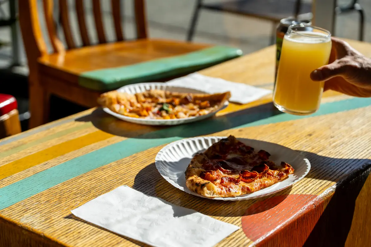 Pizza with a glass of craft beer and a can on a table at Ballard Beer Box in Ballard, Seattle