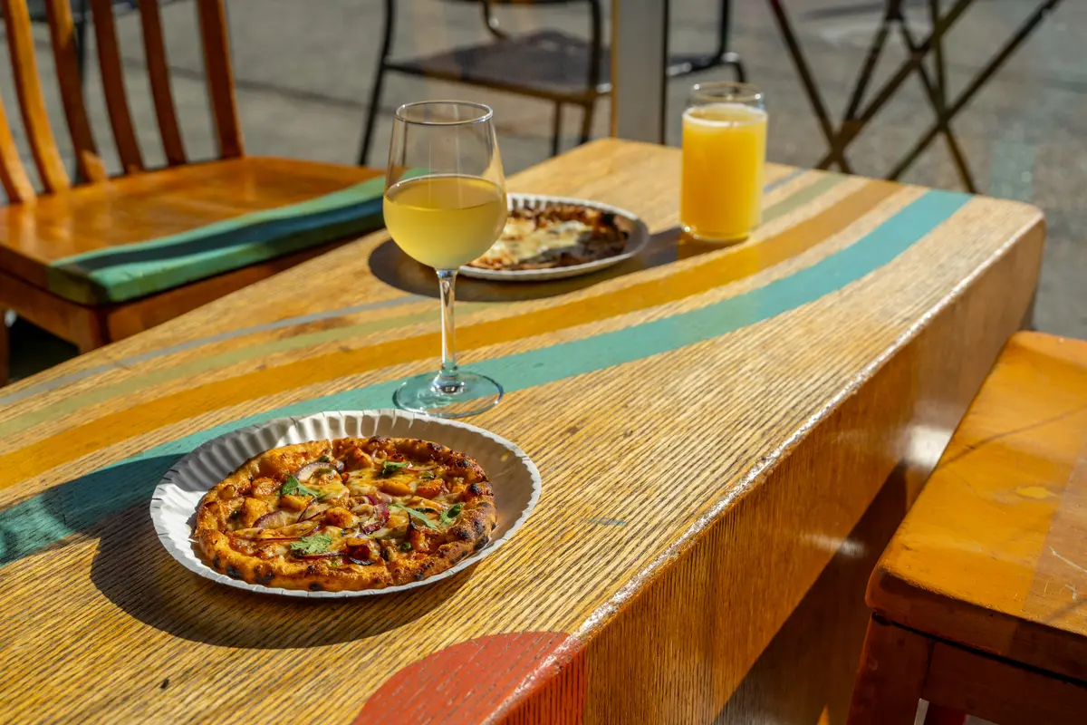 A glass of wine with pizza on a sunny table at Ballard Beer Box in Ballard, Seattle