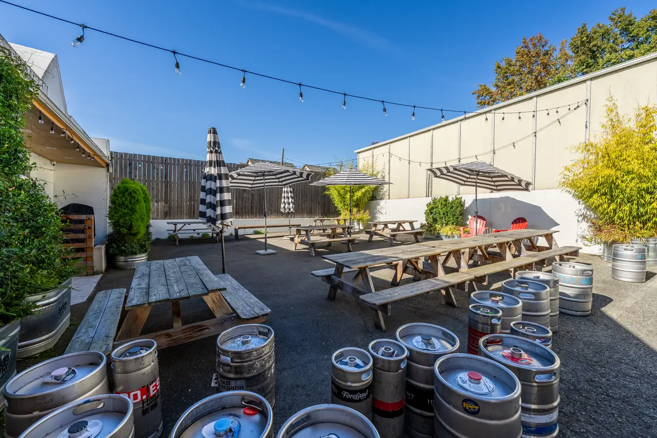 The big open-air patio at Ballard Beer Box with picnic tables and umbrellas