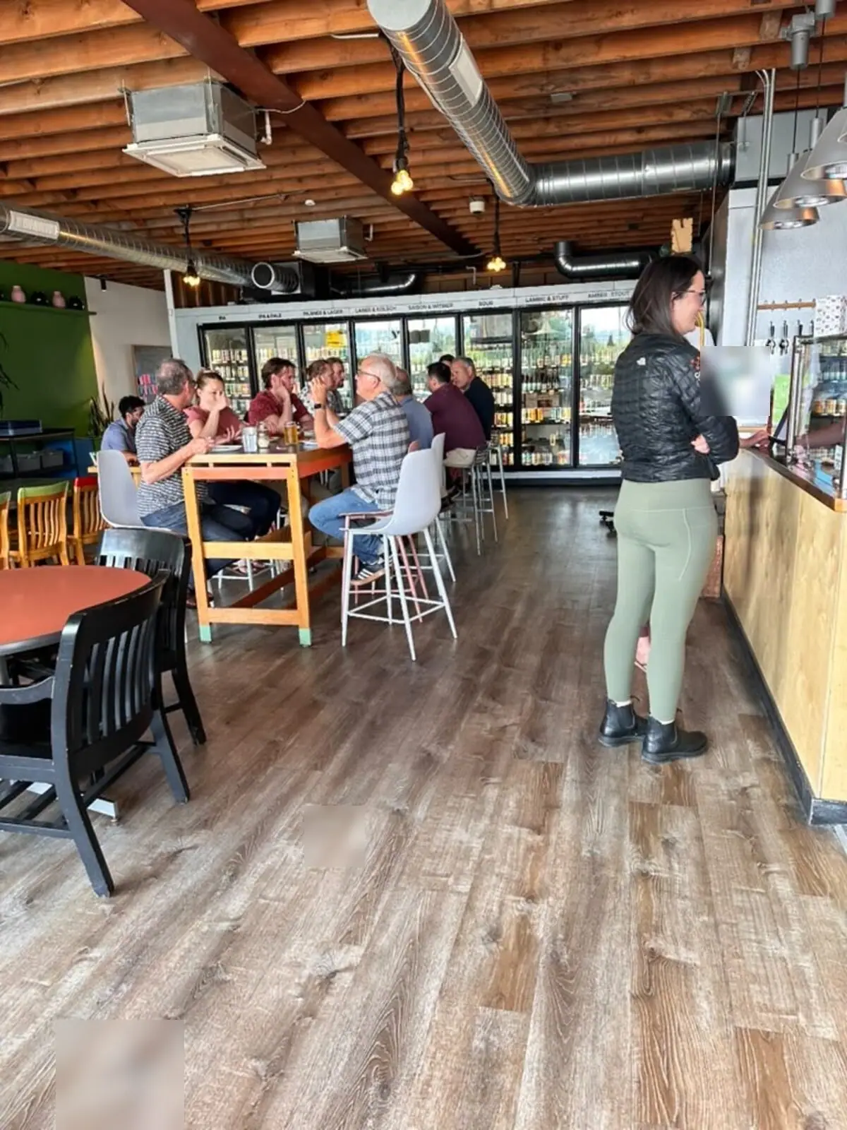 Customers at the tables inside Ballard Beer Box with the bottle fridges behind